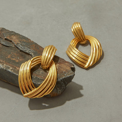 Statement sculptural gold hoops with ribbed design on stone surface
