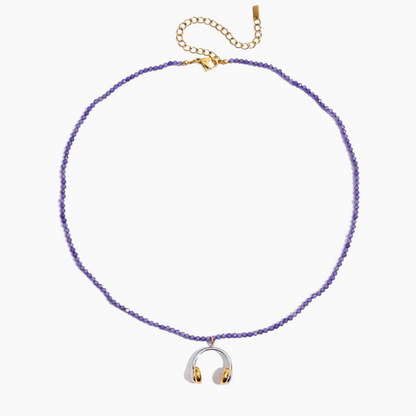Purple beaded necklace with a silver and gold pendant on a white background