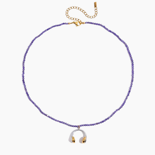 Purple beaded necklace with a silver and gold pendant on a white background