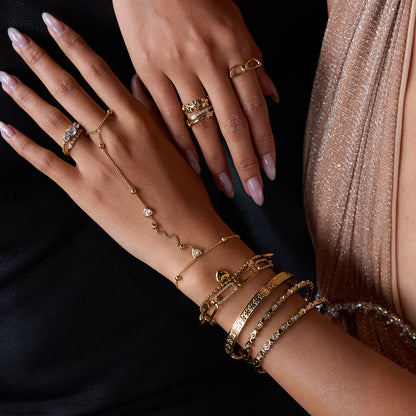 woman wearing layered gold bracelets including heart charm design