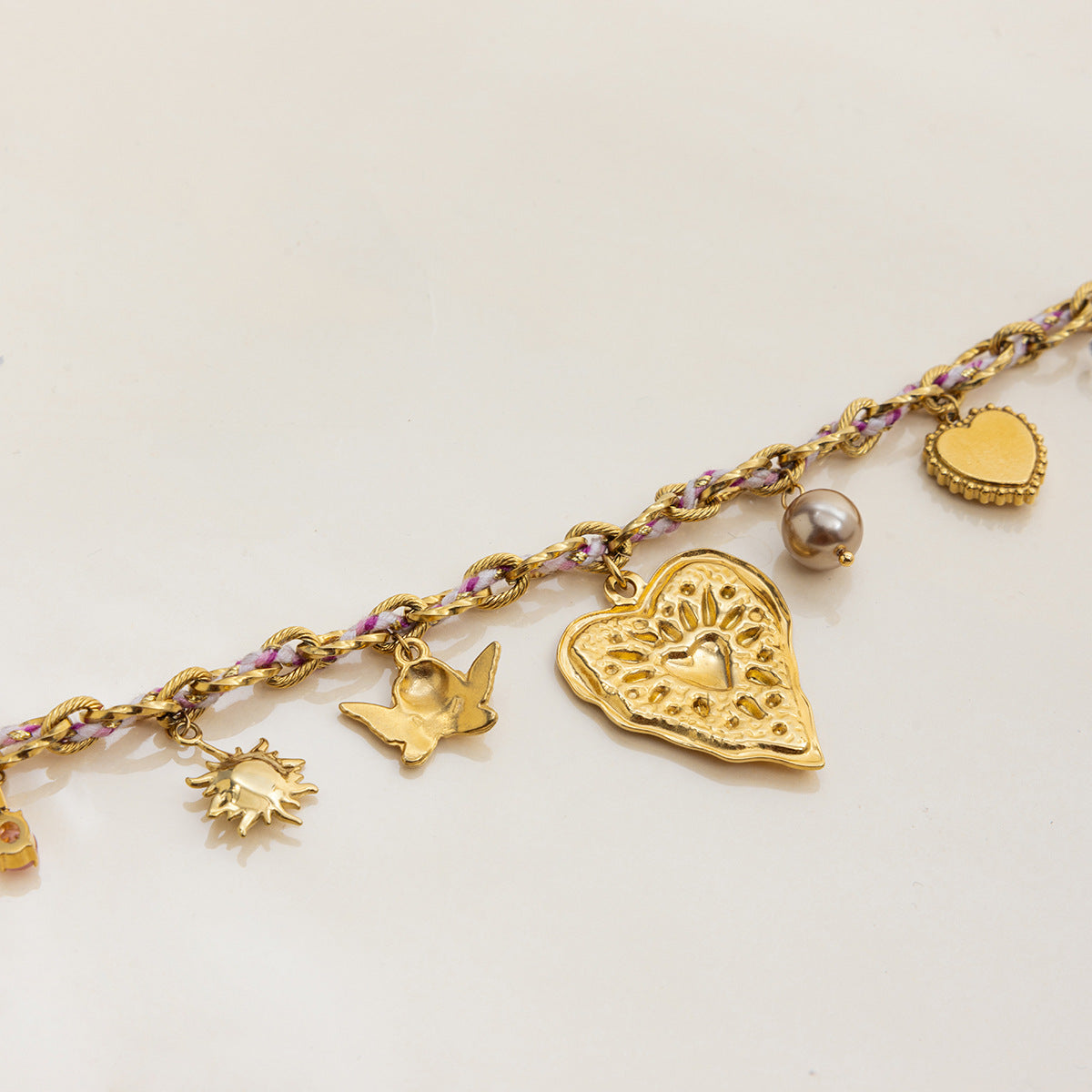 Close-up of gold charm necklace with pearl and star details