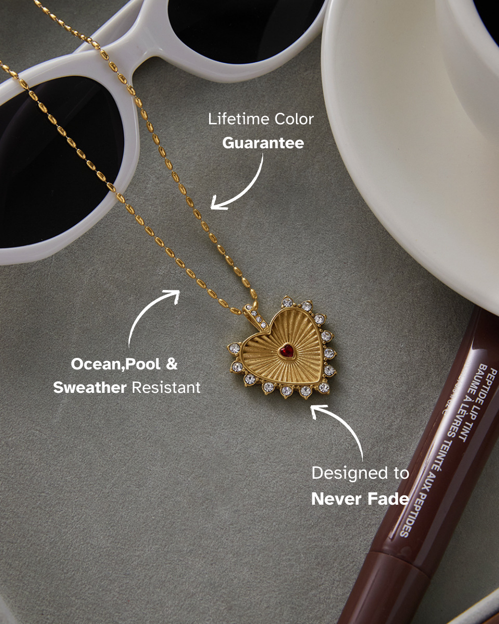 Gold necklace with a heart-shaped pendant on a gray surface with text about its features.
