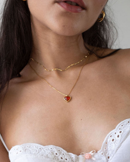 Close-up of a person wearing a gold necklace with a heart pendant.