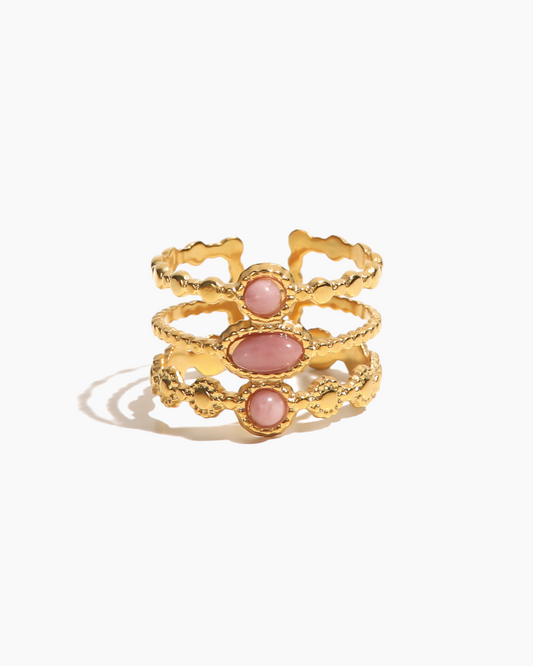 Gold ring with pink stones on a white background