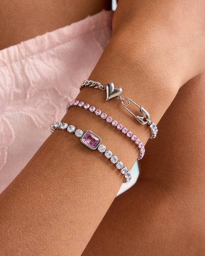 Silver heart safety pin bracelet with punk charm detail, styled on model wrist in soft pink dress