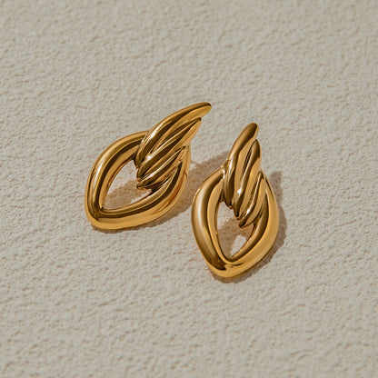 Chunky gold twisted earrings on beige textured background