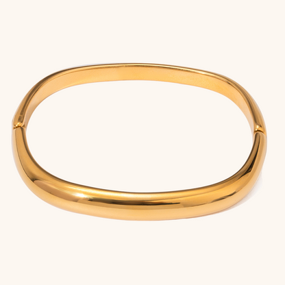 Minimalist oval gold bangle bracelet displayed on a clean beige background