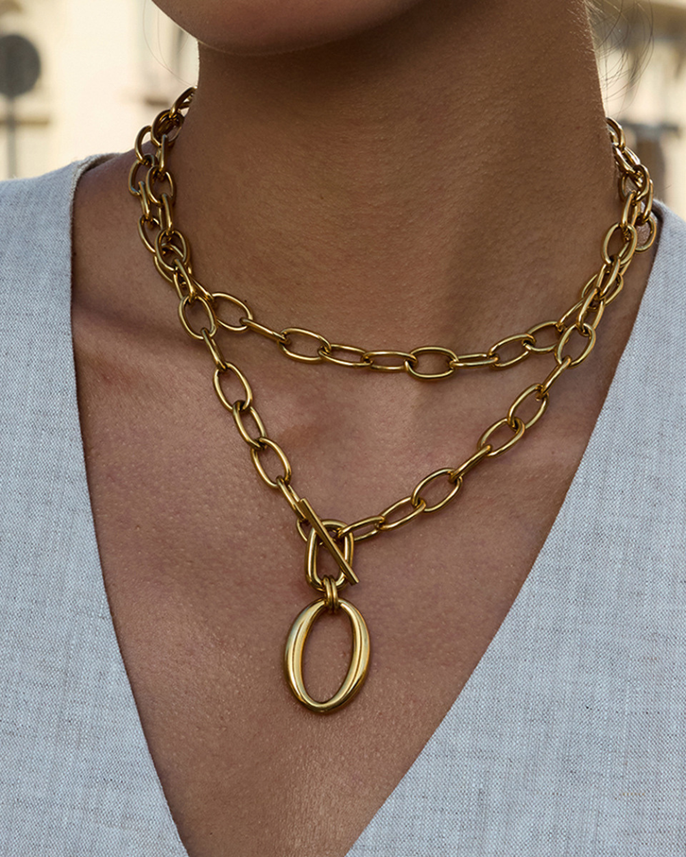 Gold chain necklace with a pendant worn by a person against a neutral background