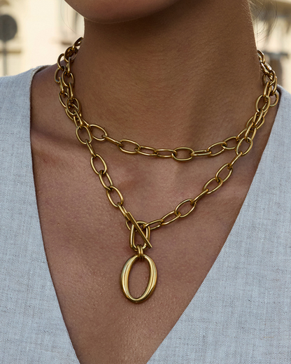Gold chain necklace with a pendant worn by a person against a neutral background