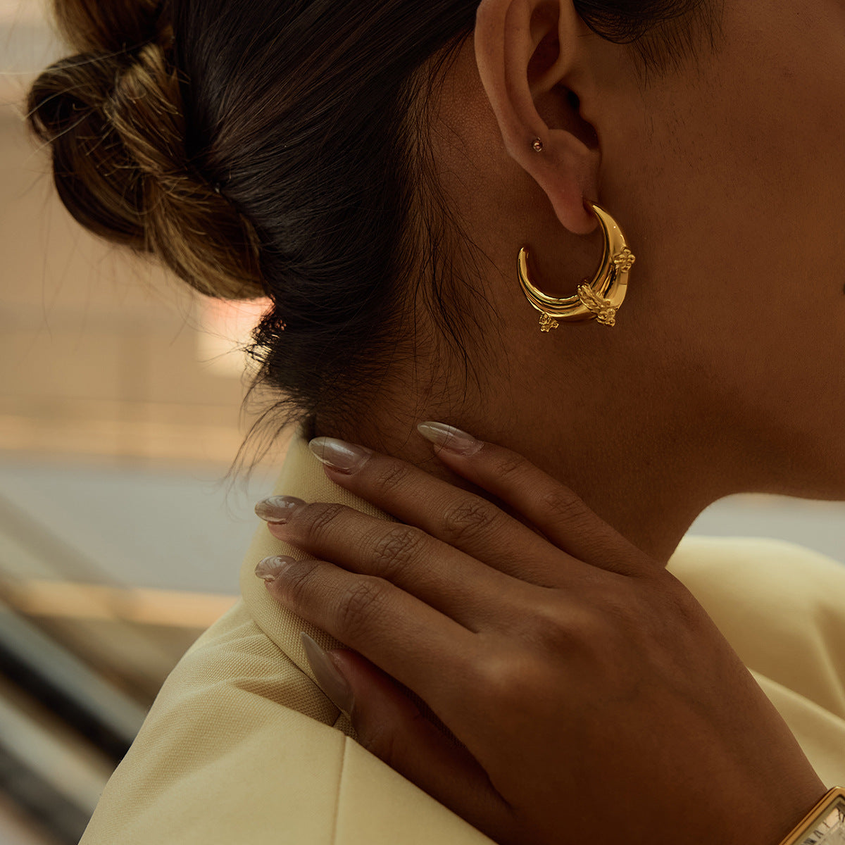 Model wearing crescent moon hoop earrings in low-light, elegant setting