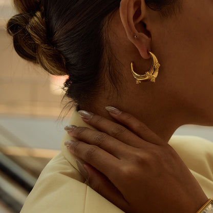 Model wearing crescent moon hoop earrings in low-light, elegant setting