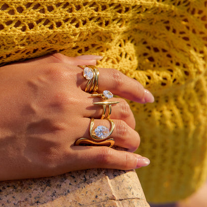 Fashion photo of model wearing layered gold rings against yellow knit