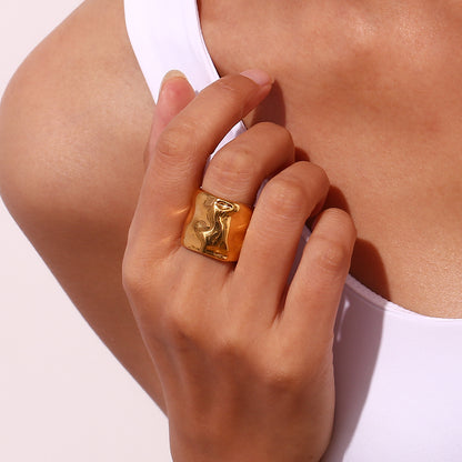Model’s finger adorned with molten open cuff ring against white blouse