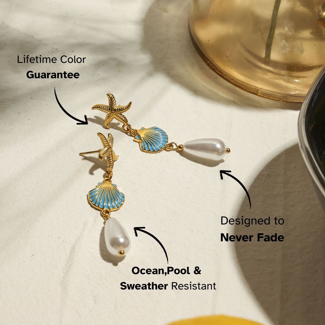 Gold sea star and shell earrings with pearl drops on marble surface – beachwear jewelry with coastal details