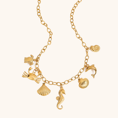Close-up of gold ocean animal charm necklace styled with pastel summer dress