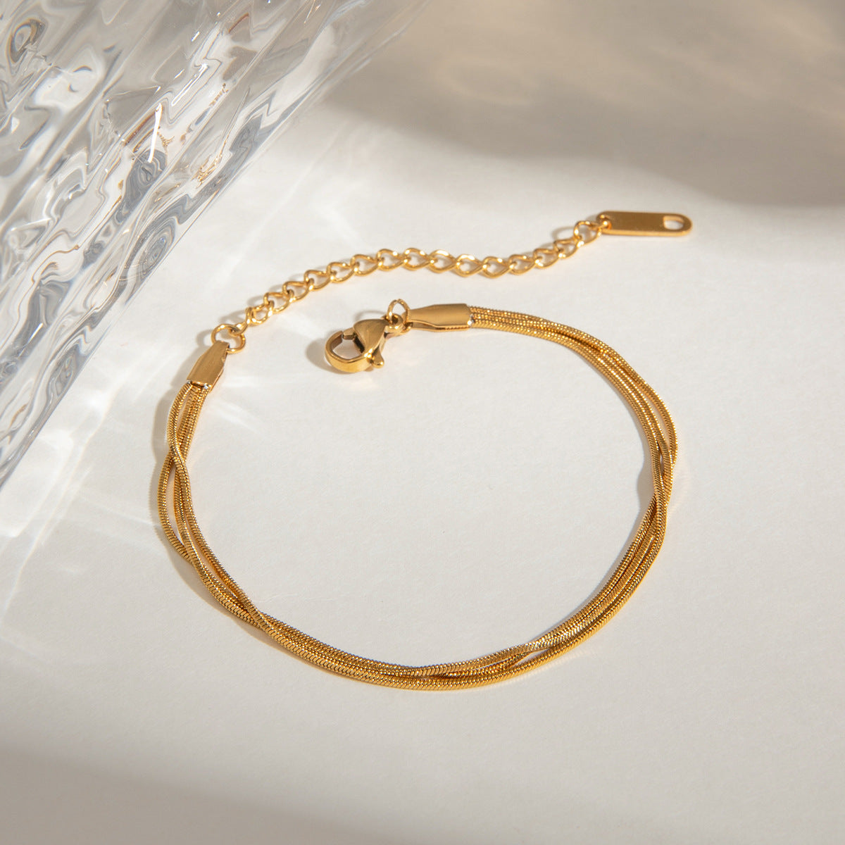 Woman posing with gold bracelet and matching necklace in neutral setting