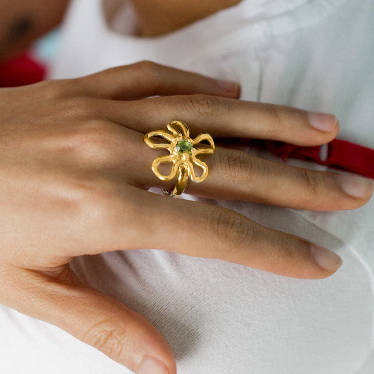 gold flower statement ring with green gemstone worn on hand