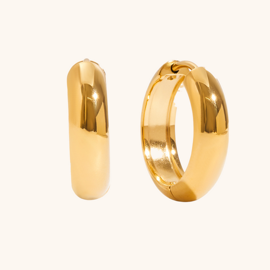 Close-up of gold chunky hoop earrings on reflective surface