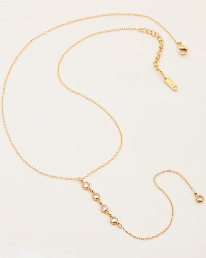 Gold necklace with small round beads on a light beige background