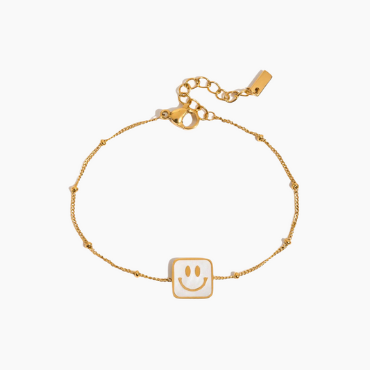 Gold bracelet with a smiley face charm on a white background