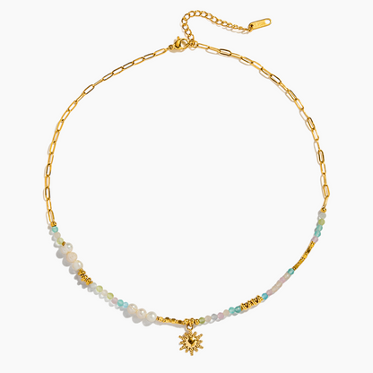 Gold necklace with beaded chain and flower pendant on a white background