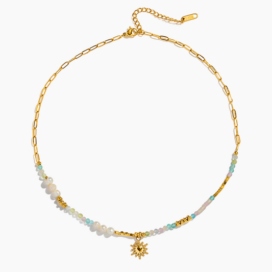 Gold necklace with beaded chain and flower pendant on a white background