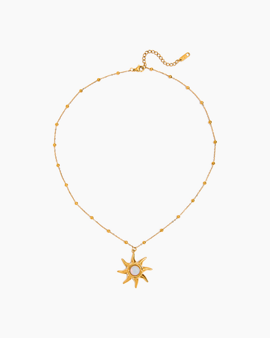 Gold necklace with a sun-shaped pendant on a white background