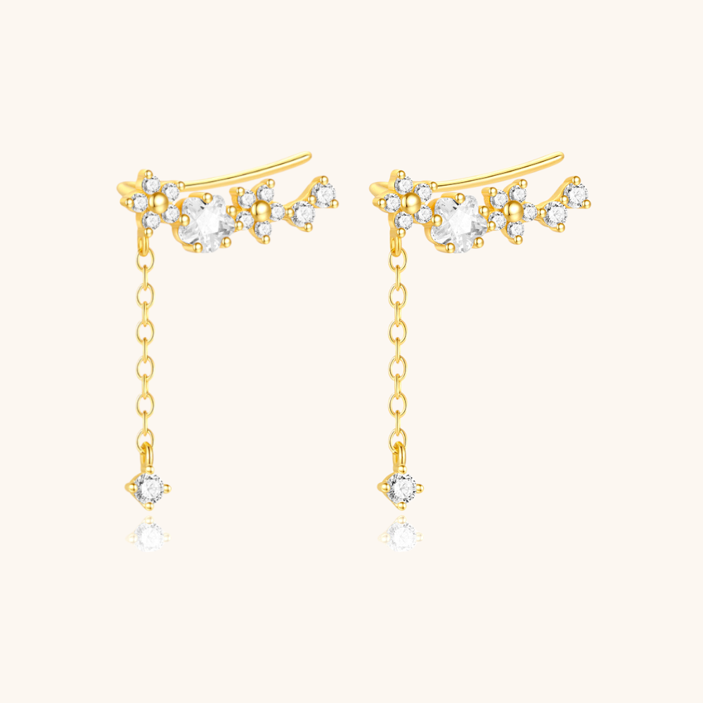 Zircon flower ear climber with hanging crystal, shown from different angle in warm light.