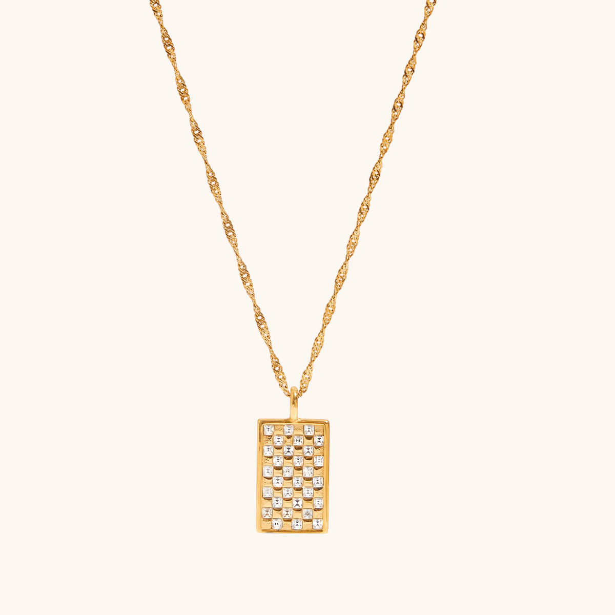 Close-up of gold grid pendant necklace with shiny crystal accents on white fabric.