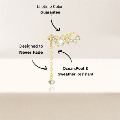 Asymmetric gold ear cuff with long dangle chain and zircon stones, close-up view