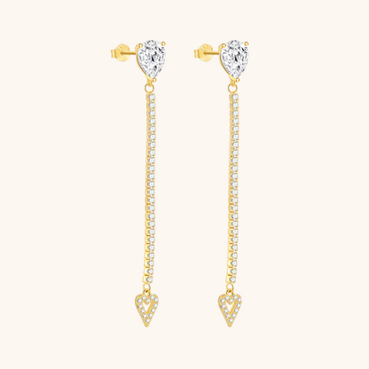 Close-up of long heart-shaped drop earrings with pear-cut stud and crystal detailing, worn with blonde hair