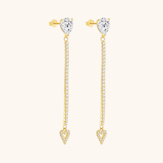 Close-up of long heart-shaped drop earrings with pear-cut stud and crystal detailing, worn with blonde hair