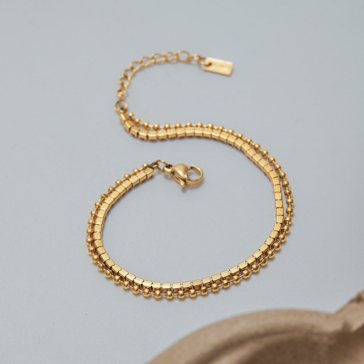 Single-layer gold bracelet with pink rhinestones on light background