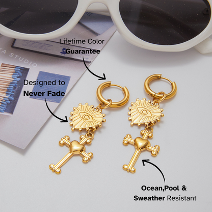 Gold earrings with religious designs on a light gray background, featuring text about color guarantee and water resistance.