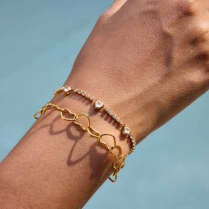 Gold heart chain bracelet stacked with zircon heart tennis bracelet on model wrist