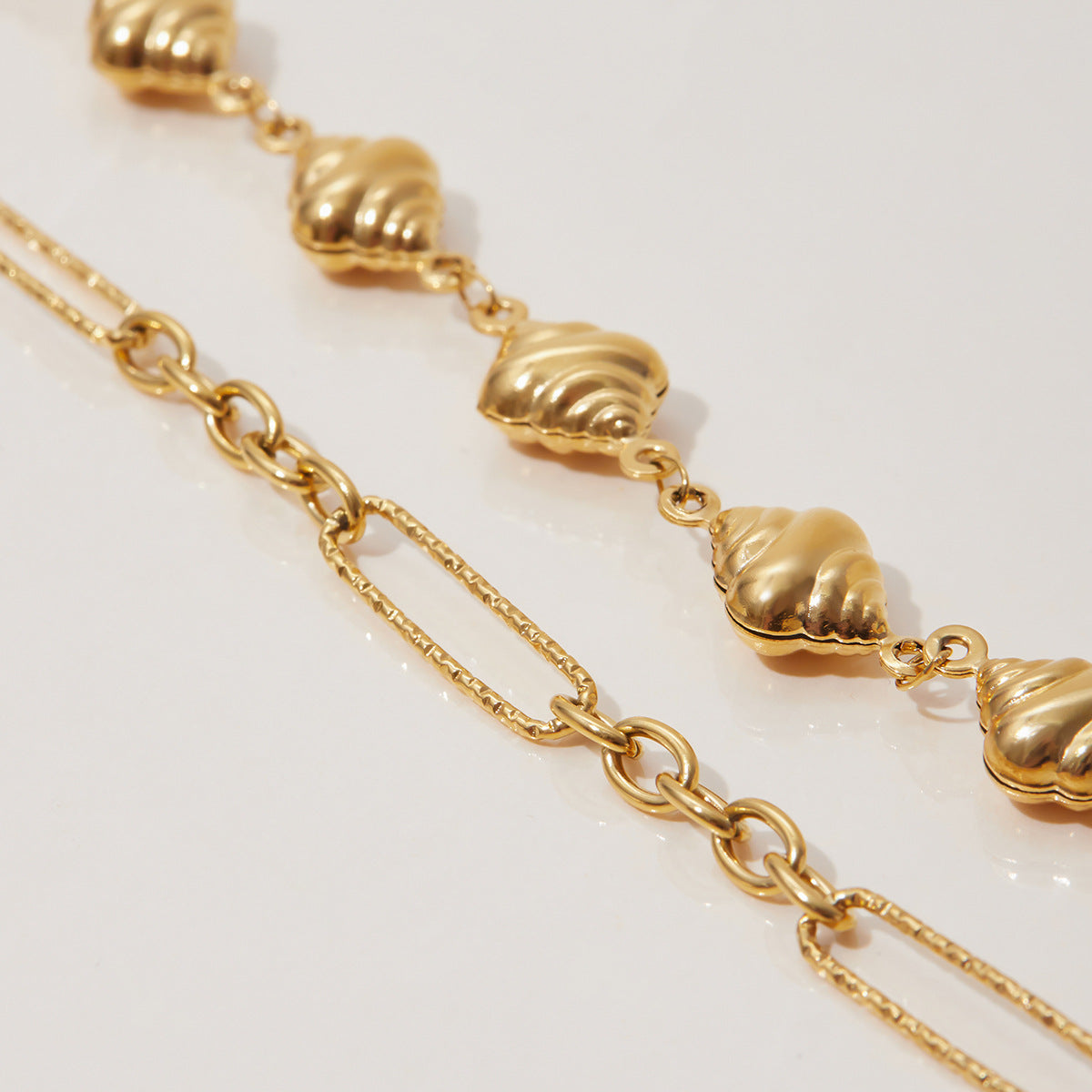 Sleek gold bracelet stacked with beaded accessories in natural light.
