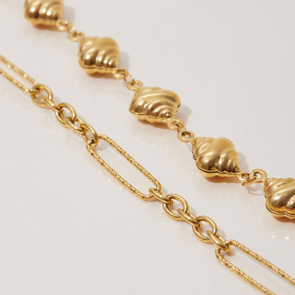 Sleek gold bracelet stacked with beaded accessories in natural light.