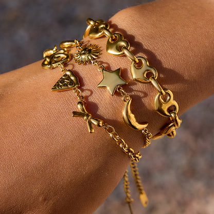 Model wearing multiple gold charm bracelets outdoors