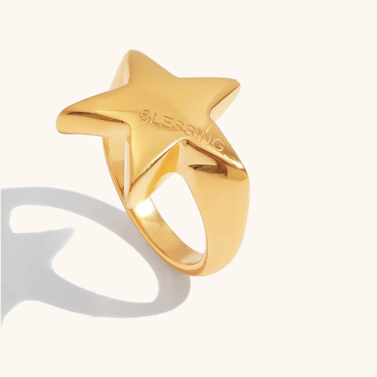 Gold star-shaped ring with "BLESSING" engraving, styled beside lipstick and watch
