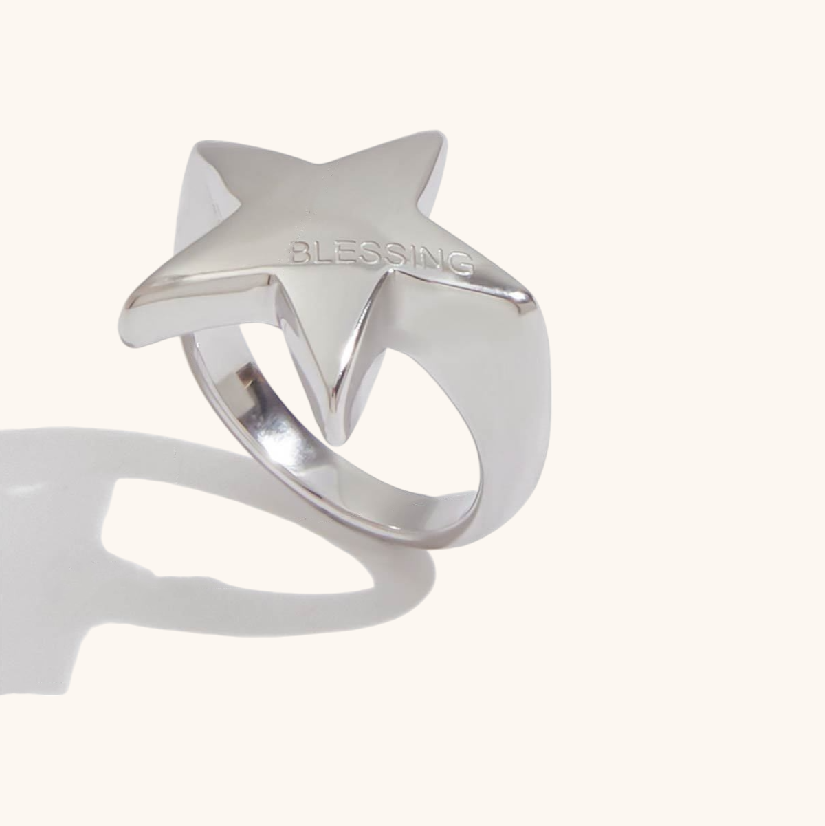 Silver star ring with BLESSING engraving styled in flat lay with gold accessories