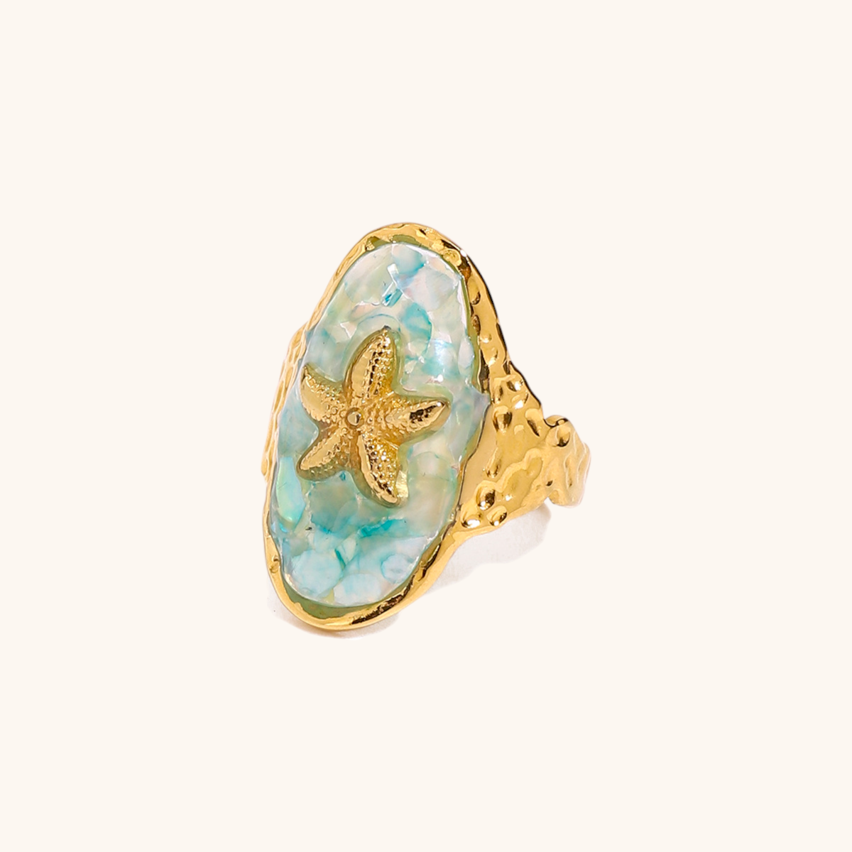Gold starfish ring with aqua shell resin, styled on a flat surface with pearls and seashells