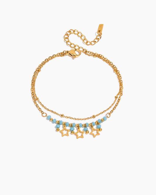 Gold bracelet with star and bead details on a white background