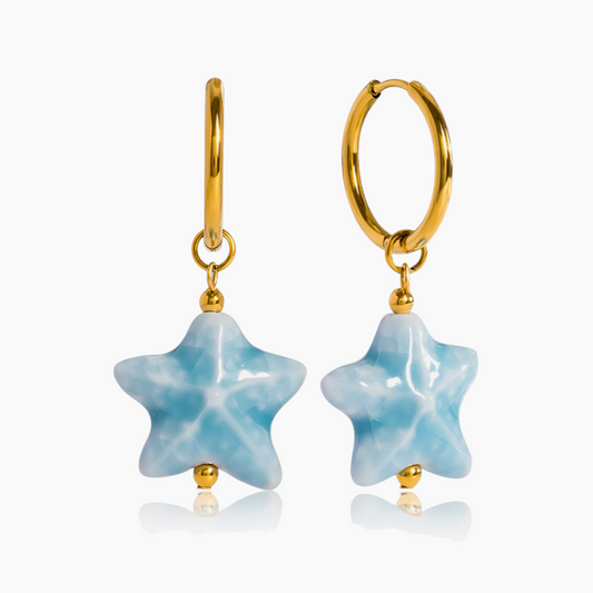 Gold hoop earrings with star-shaped blue stones on a white background
