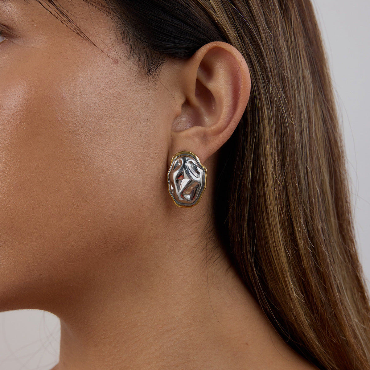 woman wearing mixed-metal stud earrings with a sculptural design, lightweight and comfortable fit