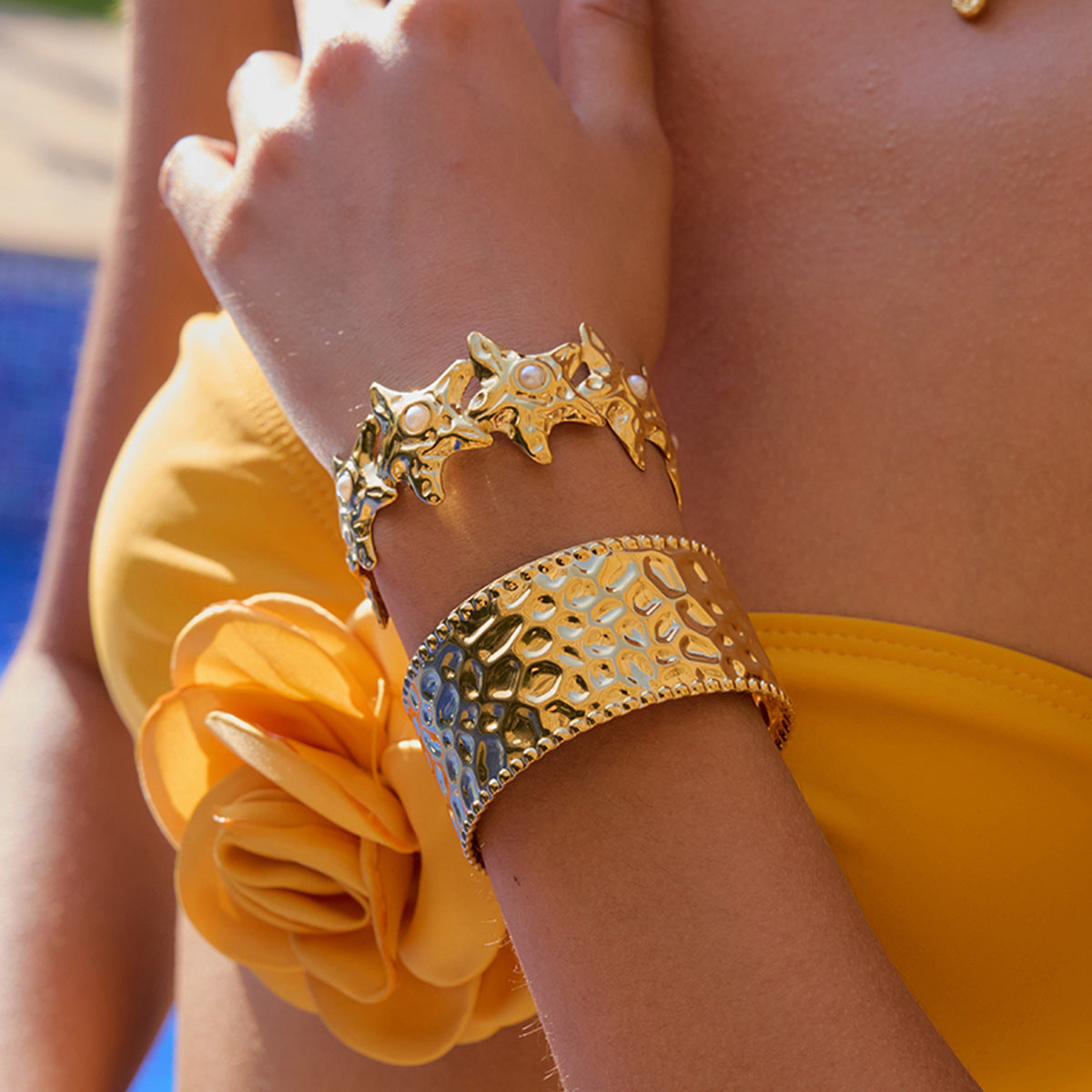 Hammered gold cuff bracelet worn with a white shirt while reading outdoors