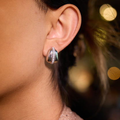 Close-up of silver statement earrings on ear with soft lighting