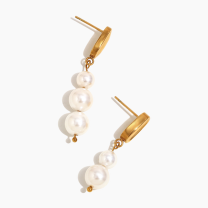 Statement pearl drop earrings displayed on neutral fabric background