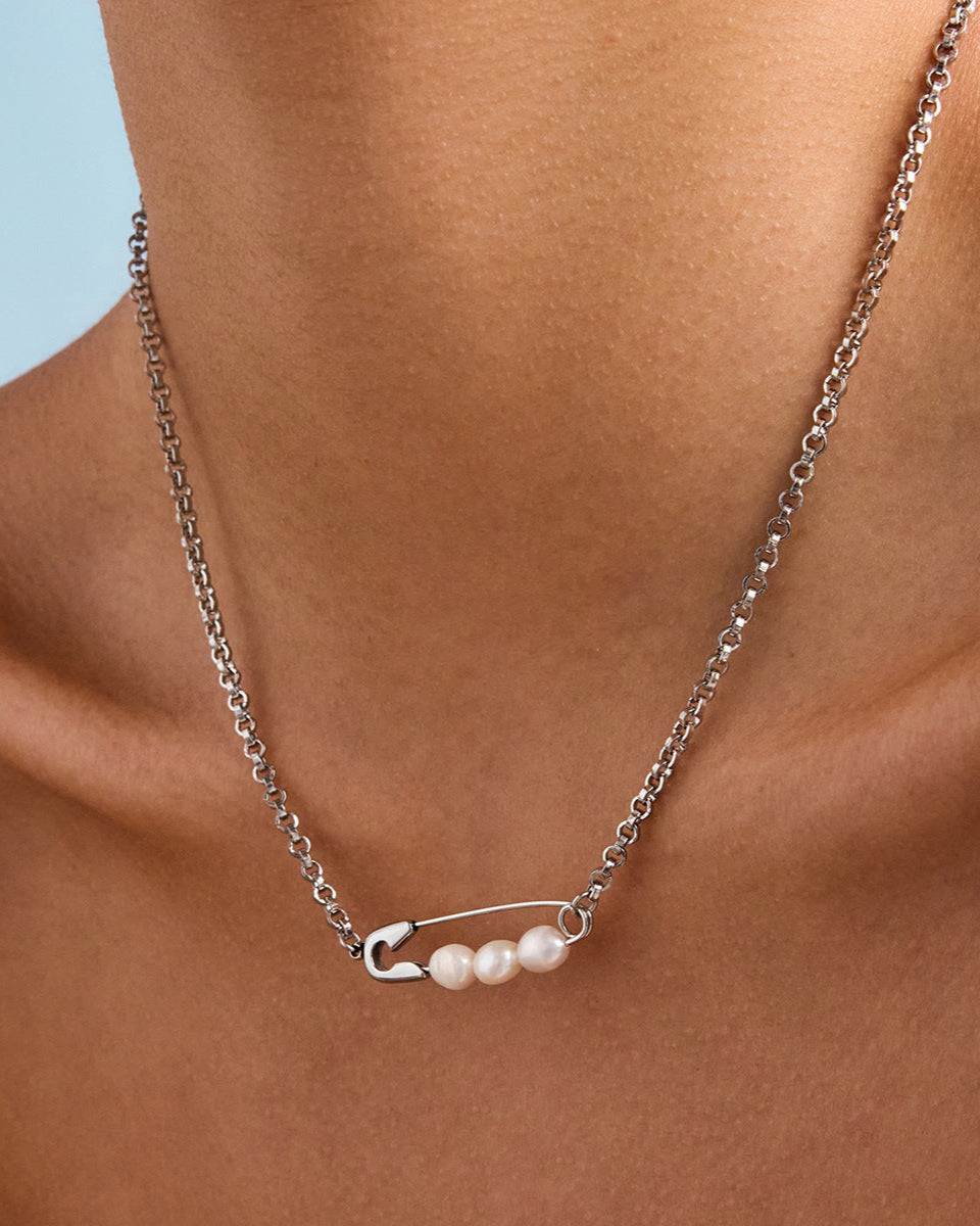 Model showing silver safety pin necklace with pearls worn as a solo statement piece on collarbone