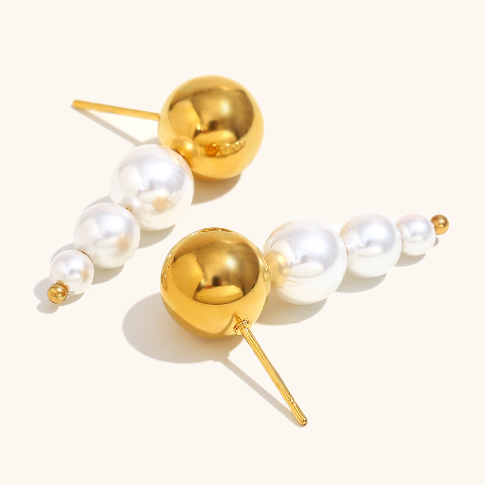 Side view of statement stud earrings featuring a gold dome and cascading pearls in a minimalist setting.