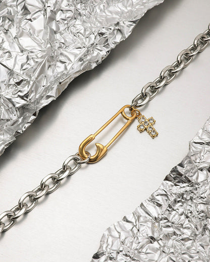 Close-up of model wrist stacking the gold and silver bracelet with rhinestone cross, styled with pastel dress.